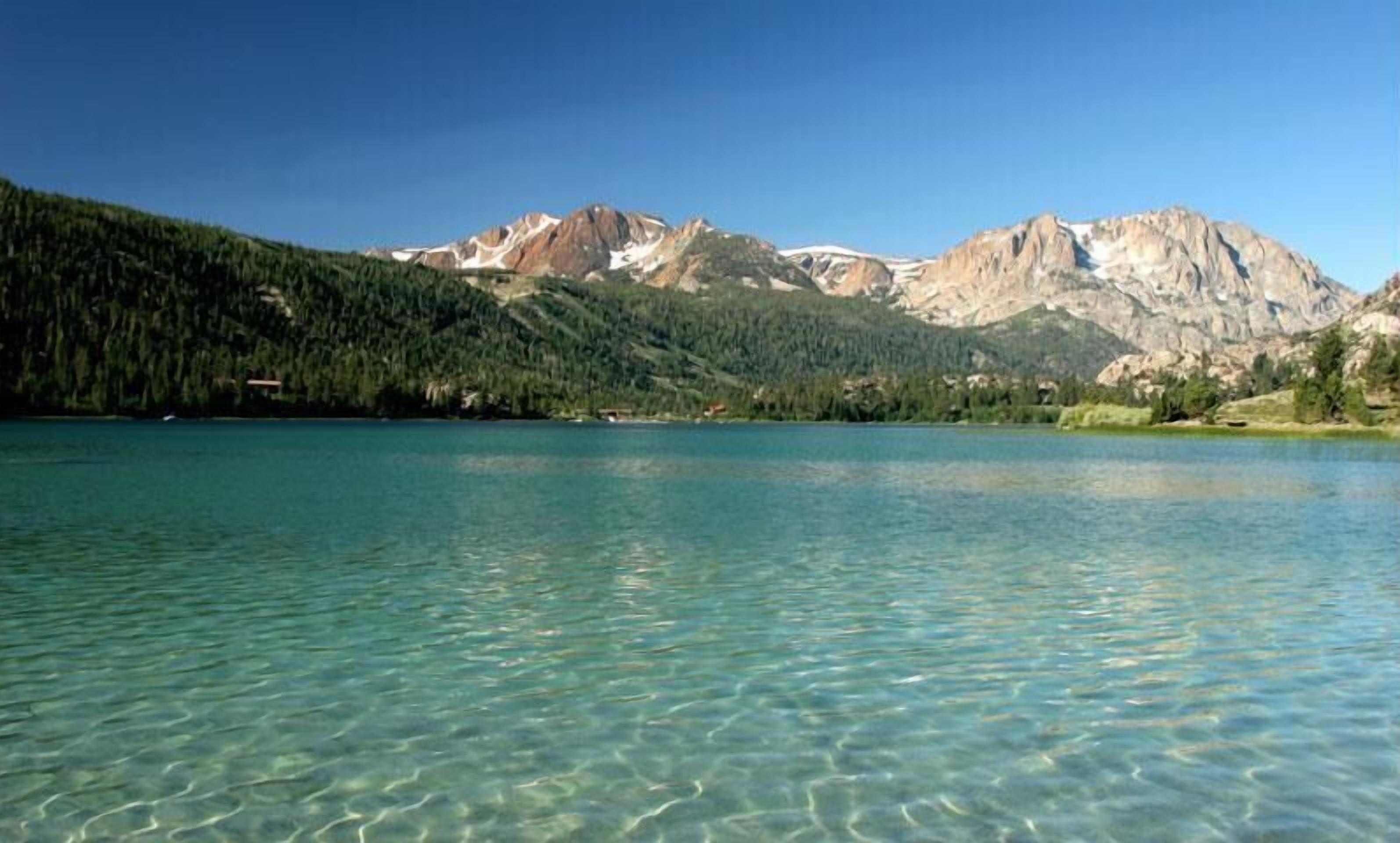 A clear lake with mountains in the background.