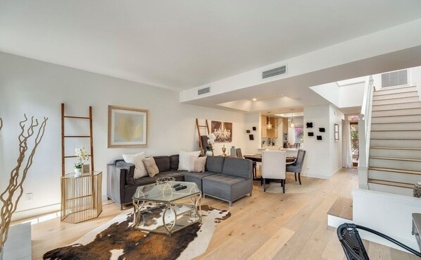 A modern living room with a sofa, coffee table, and a staircase leading to an upper floor.