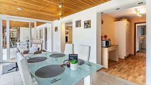 Una cocina moderna con un microondas, un refrigerador blanco y un comedor con una mesa de vidrio y sillas.