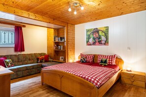 Une pièce aux murs lambrés, avec un lit, un canapé et une bibliothèque.