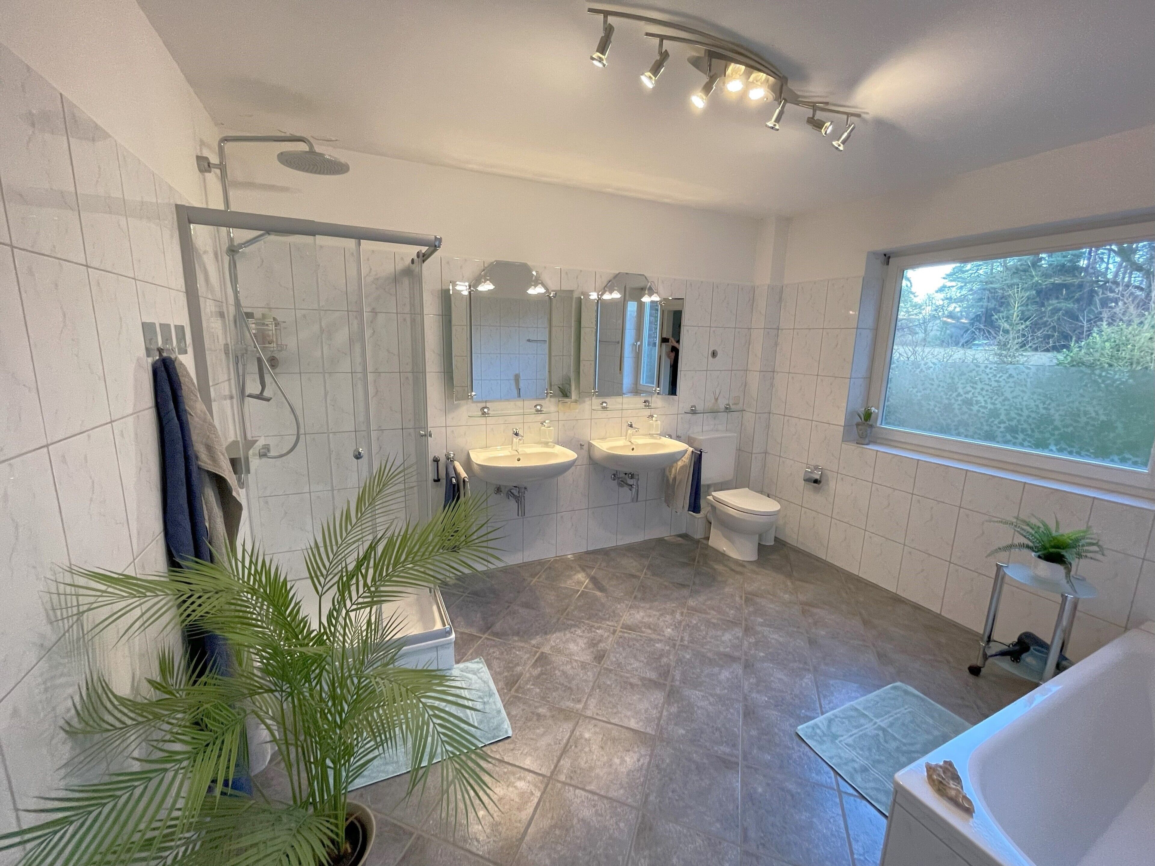 Un baño moderno con ducha, dos lavamanos, inodoro y bañera.
