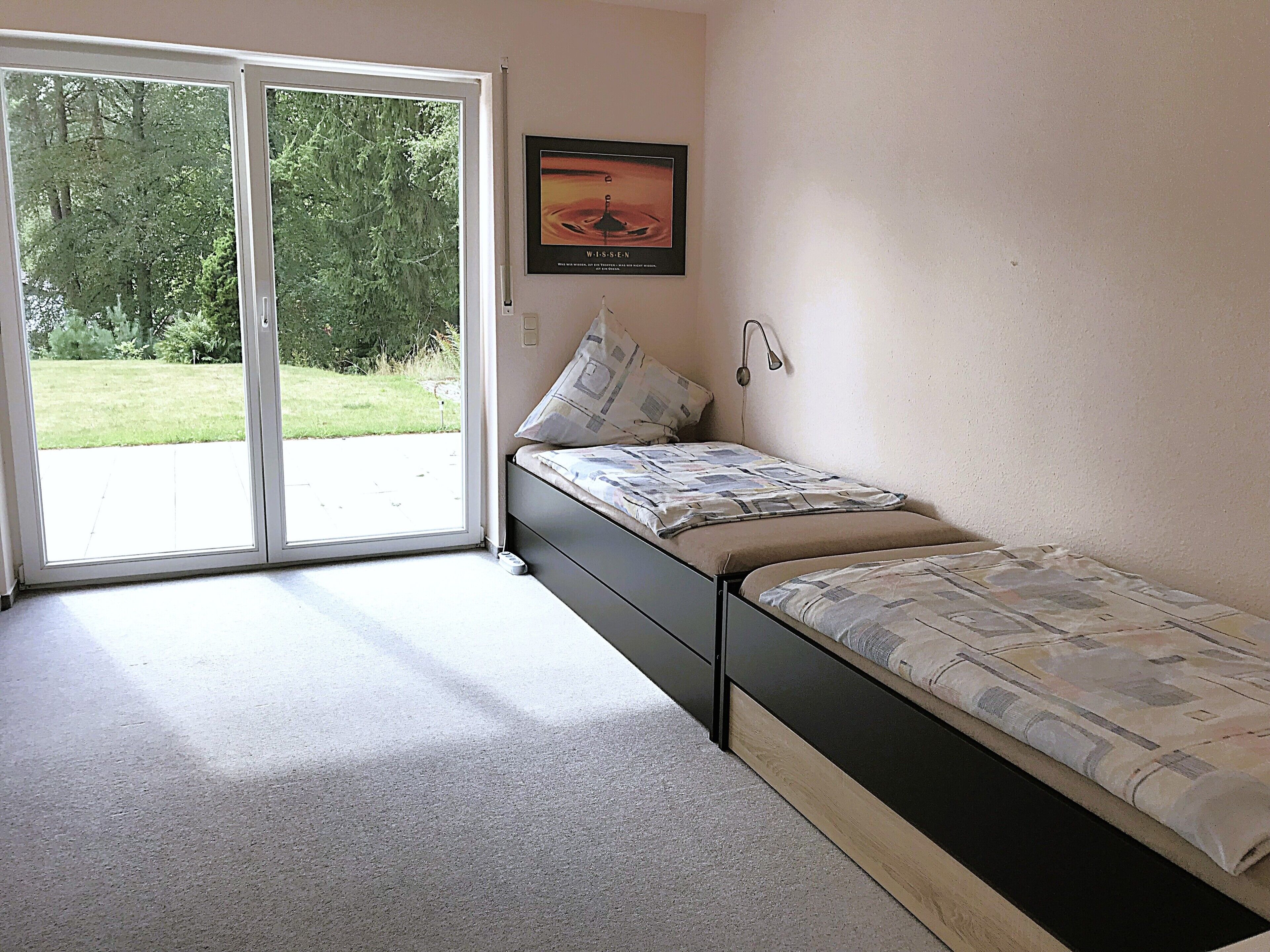 Un dormitorio con una cama, una ventana y una puerta que da a un jardín.