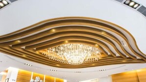 A modern hotel lobby with a unique ceiling design, a central chandelier, and a reception desk. - Royal Fine Hotel (Kaohsiung)