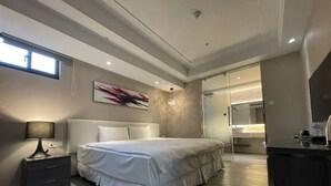 A modern bedroom with a large bed, bedside tables, a desk, and a bathroom visible through a glass door. - Royal Fine Hotel (Kaohsiung)