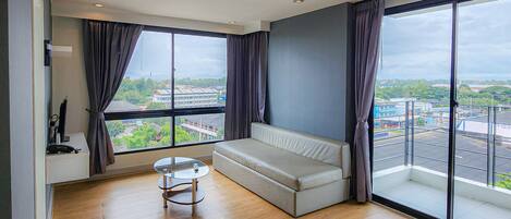 A modern room with a large window, a sofa, a small table, and a TV.