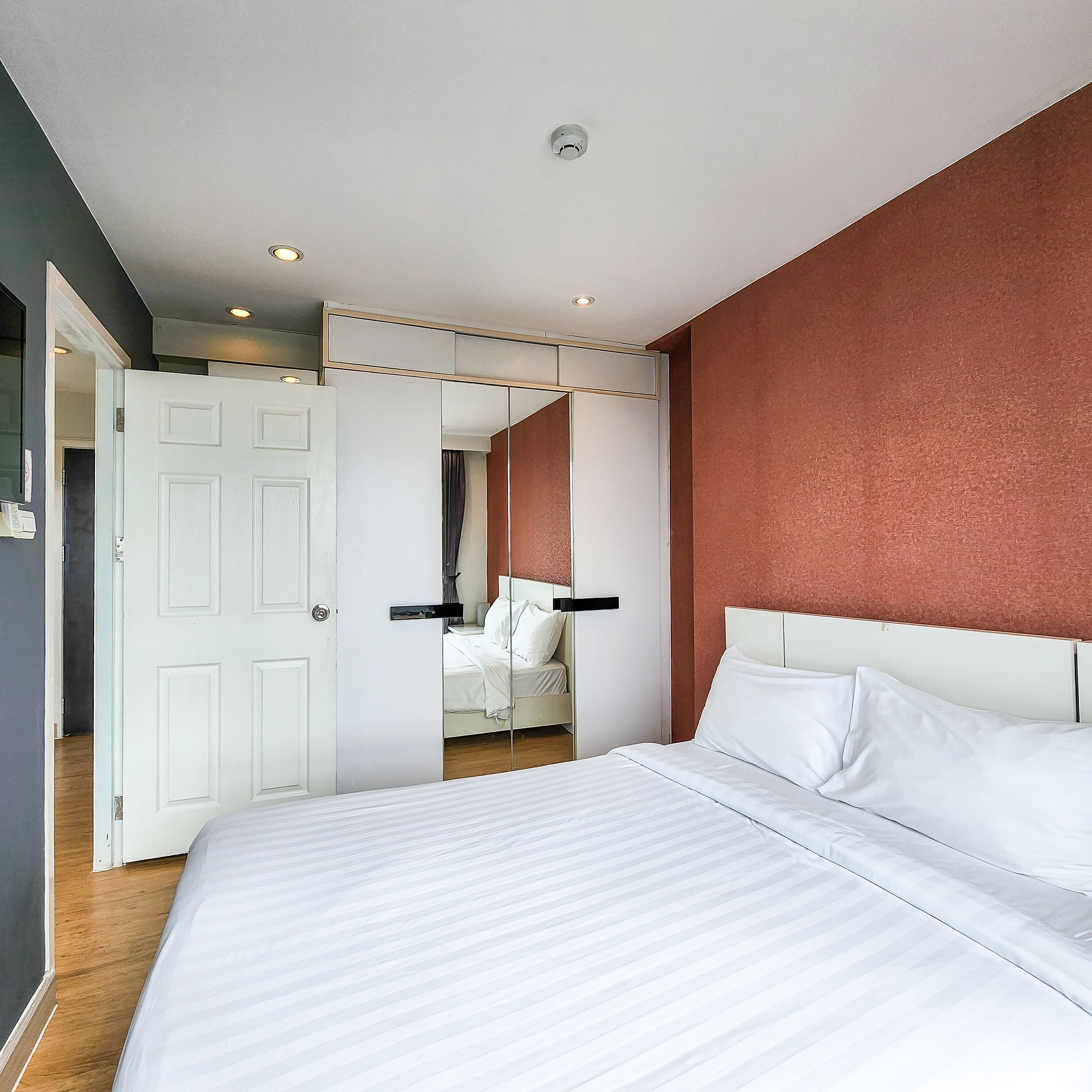 Quarto com cama grande, guarda-roupa e espelho.