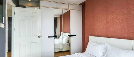 Quarto com cama grande, guarda-roupa e espelho.