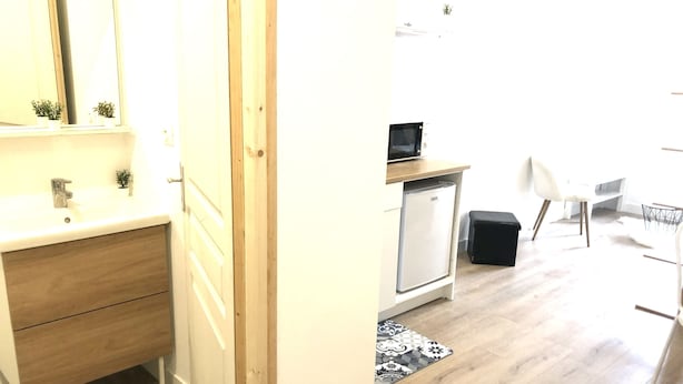 Moderni keittiö, jossa on valkoinen työtaso, puukaapit ja sisäänrakennettu mikroaaltouuni.