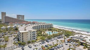 A hotel with a curved building, a pool, and a beach view.