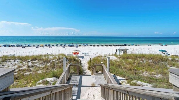 A beach with a wooden walkway leading to the shore.
