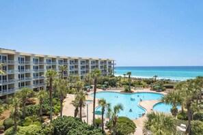 Un hôtel doté d’une piscine, de palmiers et offrant une vue sur l’océan.