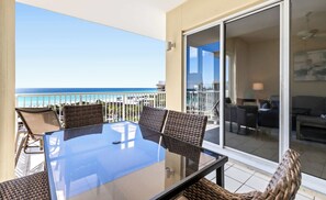 A balcony with a glass table and wicker chairs, overlooking a beach and ocean. - The Crescent 412 (Miramar Beach)