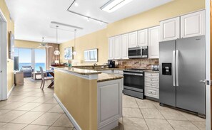 A modern kitchen with white cabinetry, stainless steel appliances, and a view to the outside.