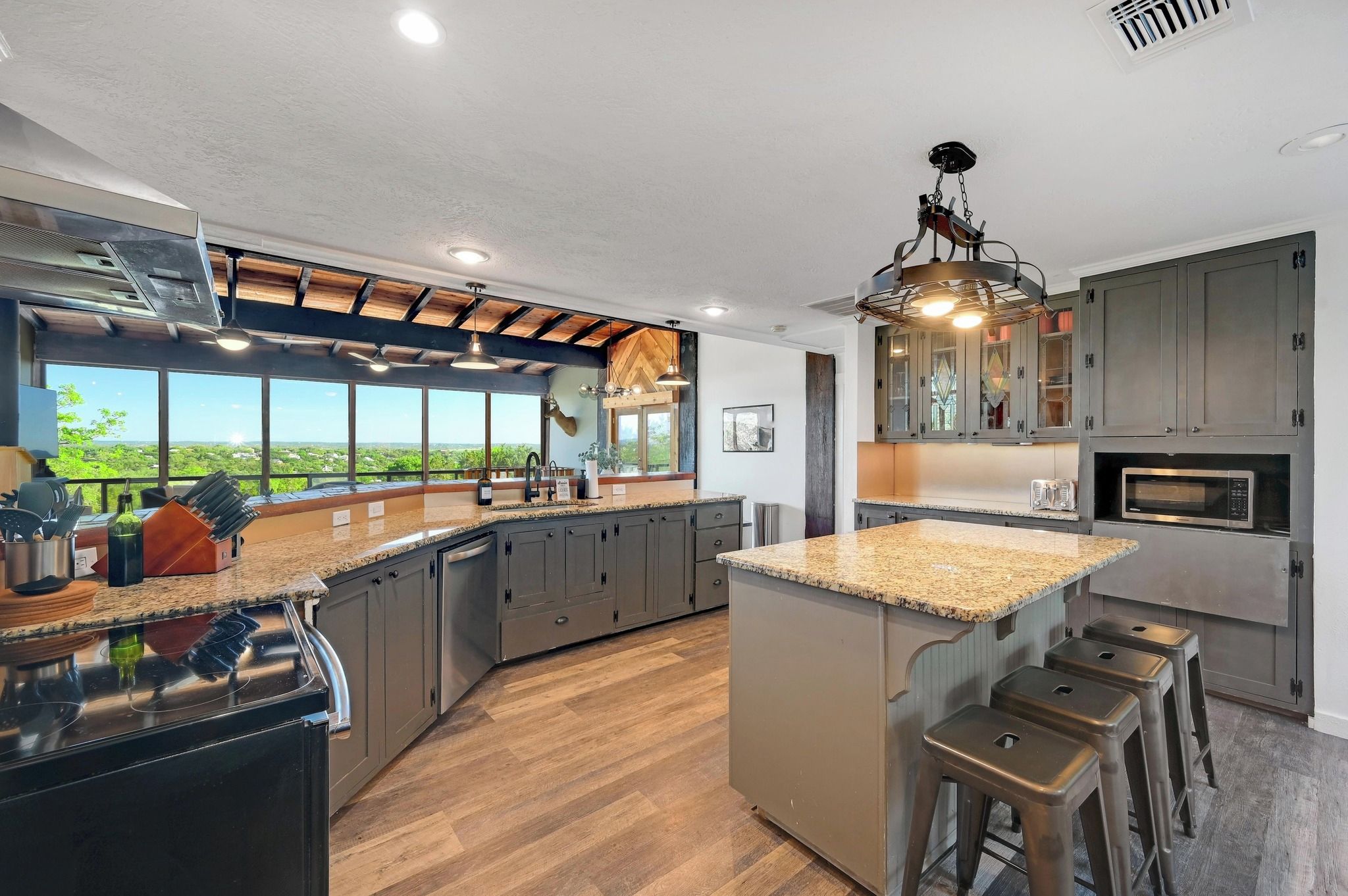 Een moderne keuken met een groot eiland, ingebouwde apparatuur en uitzicht op de omgeving.