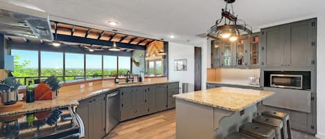 Een moderne keuken met een groot eiland, ingebouwde apparatuur en uitzicht op de omgeving.