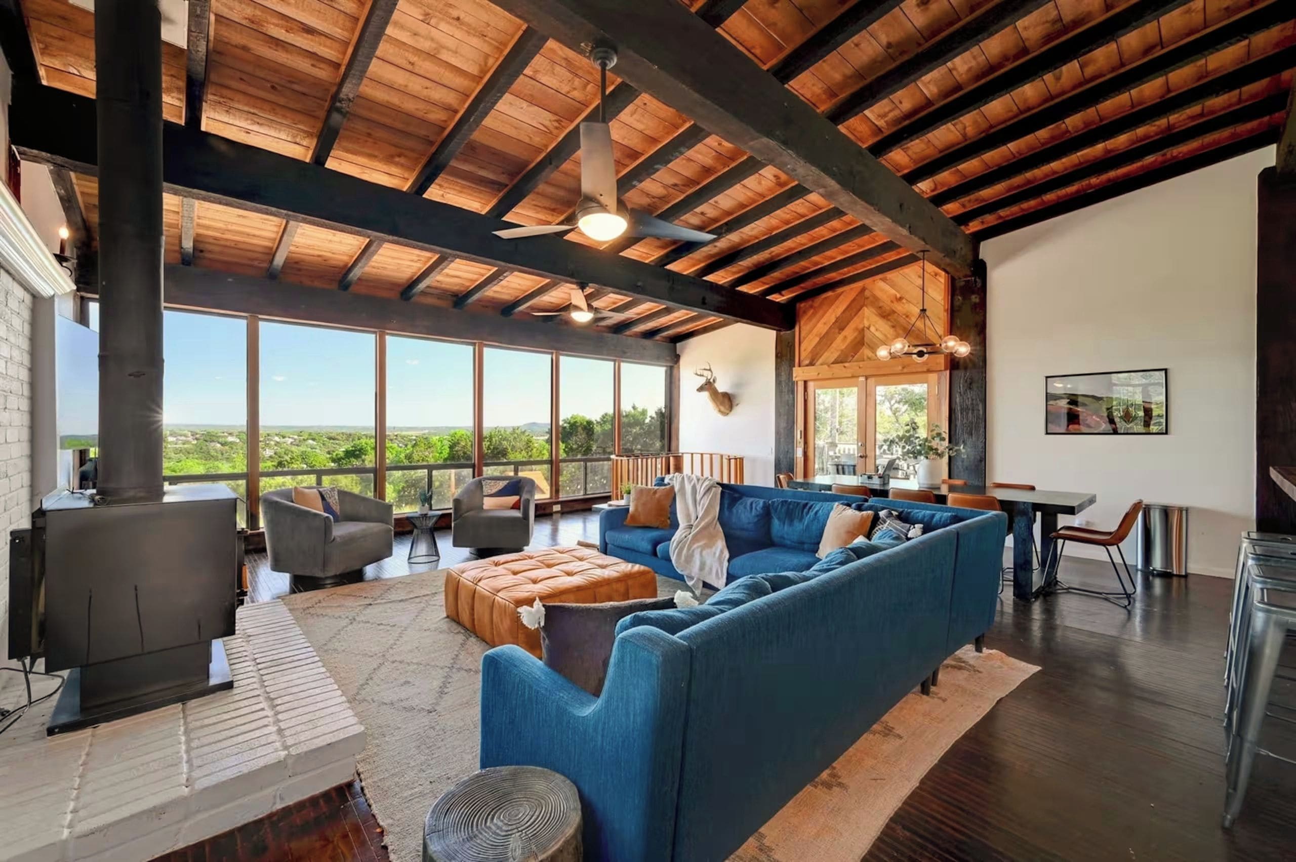 Un espacio habitable amplio con un sofá azul grande, una chimenea y vistas al exterior.