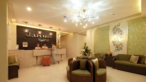 Un espace d’accueil d’hôtel au design moderne, comprenant un comptoir d’accueil, un coin salon et des œuvres d’art décoratives murales.