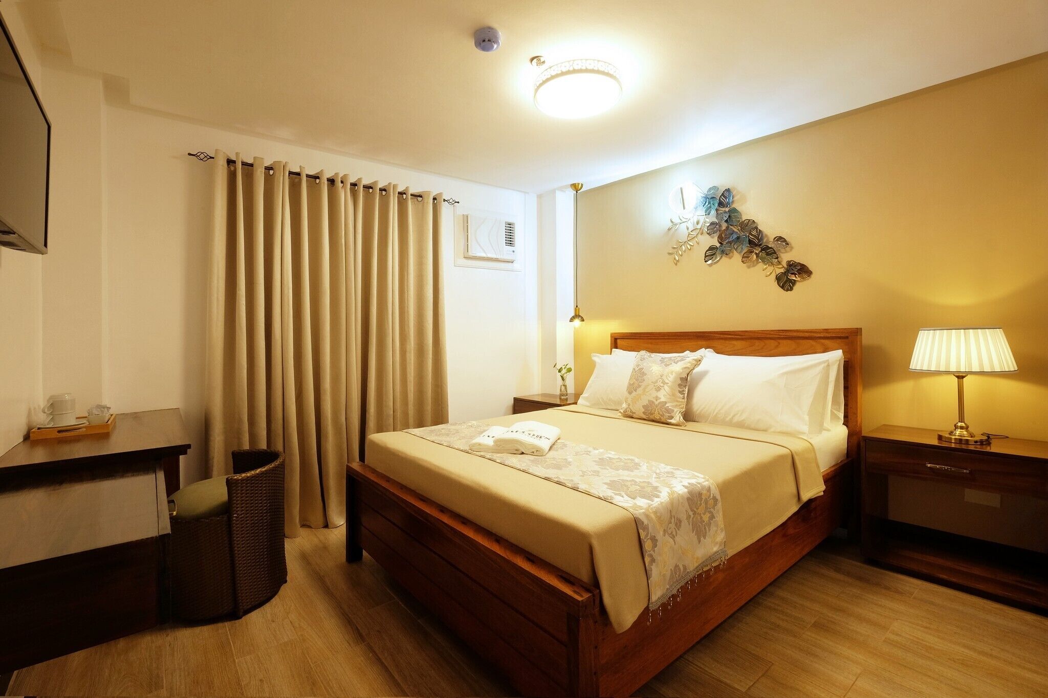 A neatly arranged hotel room with a bed, bedside table, lamp, and a desk with a chair.