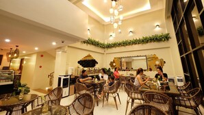 Un restaurant doté de meubles en osier, d’un lustre et d’un mur décoré de plantes.