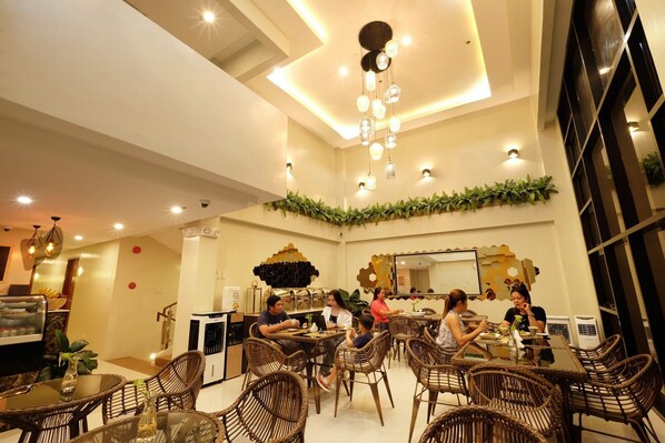 A restaurant with wicker furniture, a chandelier, and a wall decorated with plants. - Jai-cob's Suites (Coron)