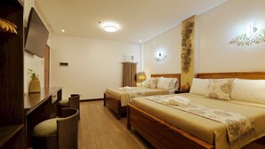 Une chambre d’hôtel avec deux lits simples, un bureau avec une chaise, une télévision et un luminaire fixé au mur.
