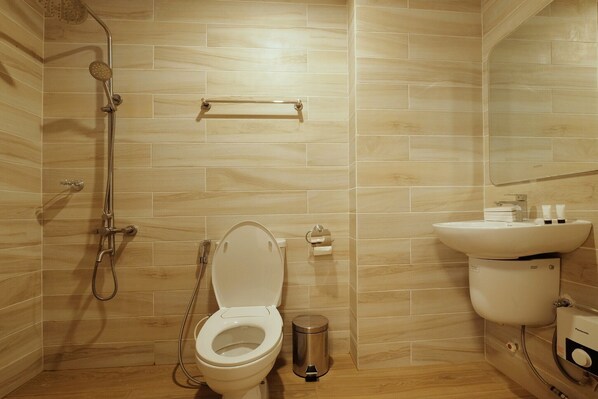 A modern bathroom with a toilet, a sink, a mirror, and a shower.