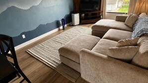 A living room with a mountain mural, a sofa, a TV, and a wooden floor. - 🏔Family Friendly - Near Airport & Lake w/ Mountain Views - No Chores (Anchorage)