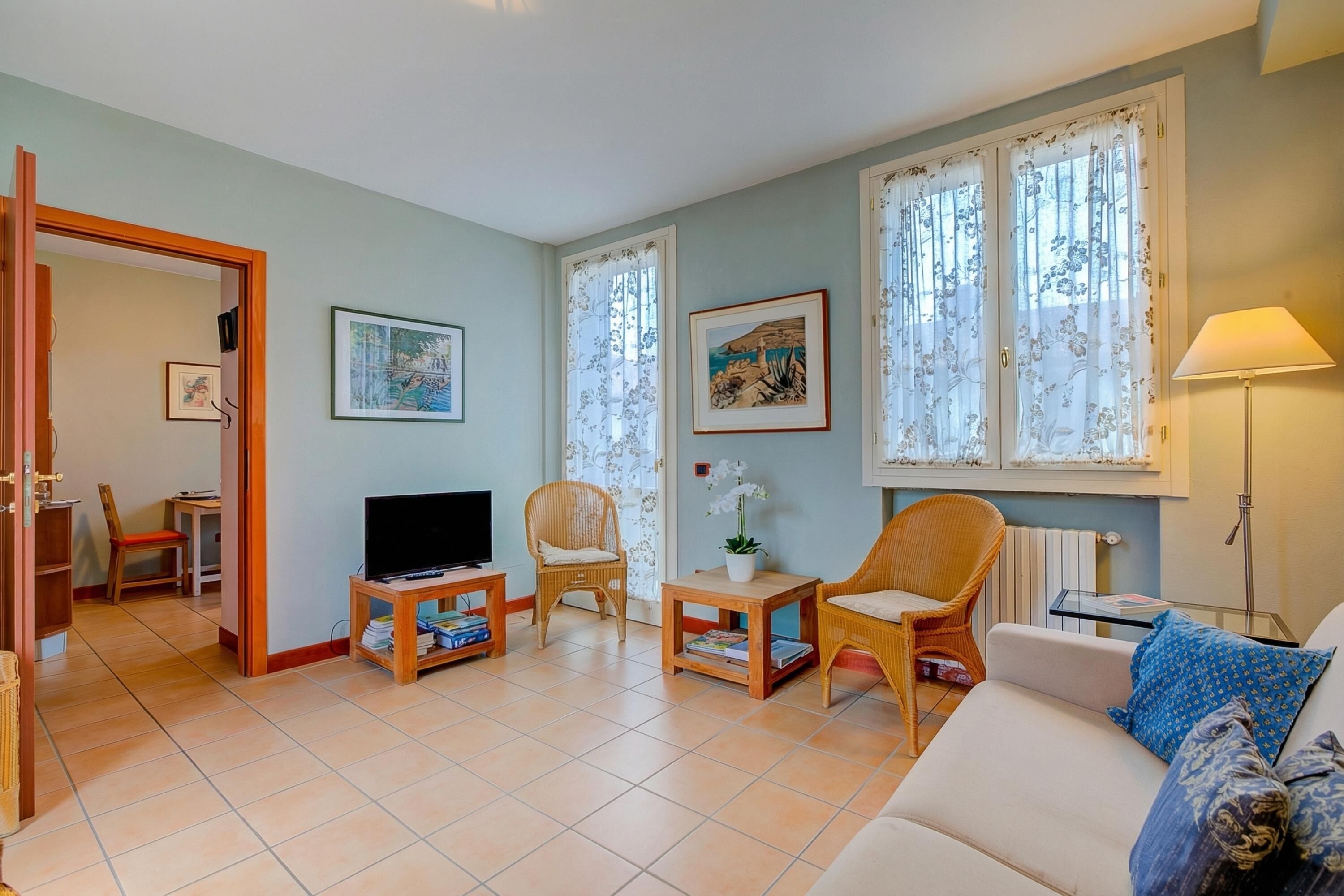 A living room with a sofa, chairs, a TV, and artwork on the walls.