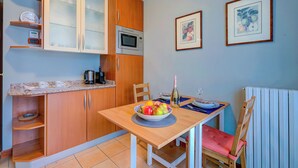 A compact kitchen with wooden cabinets, a microwave, and a fruit bowl on the table. - Porto Letizia Orchidea 3, Porlezza, Italy (Porlezza)