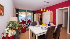 Een eetruimte met een tafel gedekt voor vier personen, stoelen, een kamerplant en uitzicht op de omgeving.