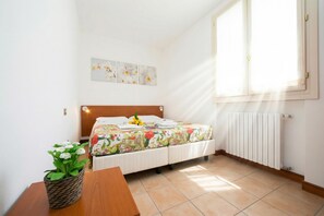 A bedroom with a bed, a window, a radiator, and a wall-mounted artwork. - Porto Letizia Begonia 6, Porlezza, Italy (Porlezza)