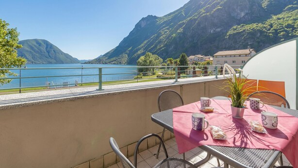 A balcony with a table set for two, overlooking a lake and mountains. - Porto Letizia P14, Porlezza, Italy (Porlezza)