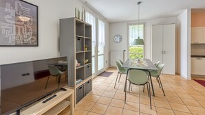 A modern kitchen with a dining table, chairs, a TV, and a bookshelf. - Porto Letizia Rosa 2, Porlezza, Italy (Porlezza)