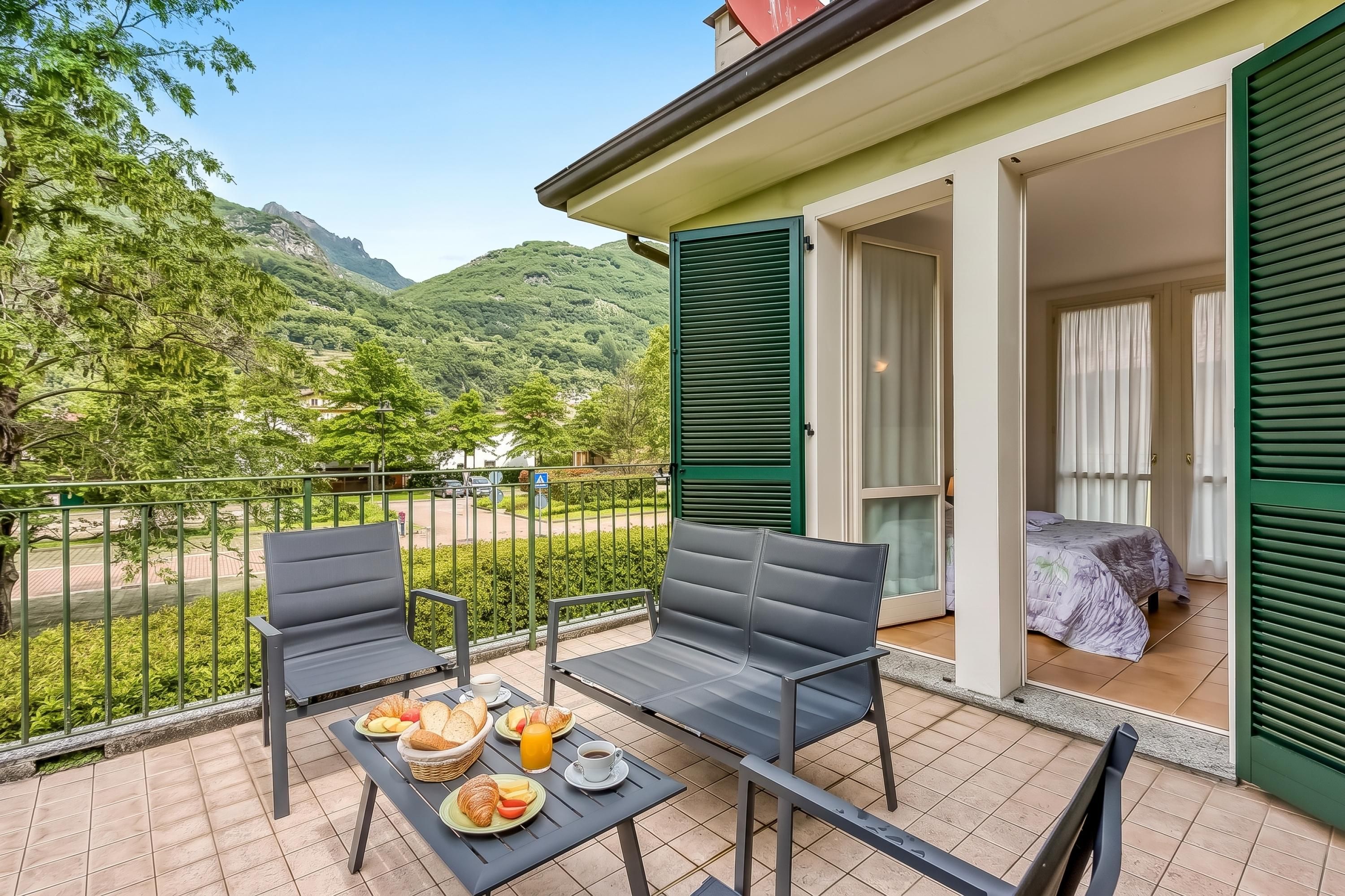 A balcony with a table set for breakfast, chairs, and a view of a mountainous landscape.