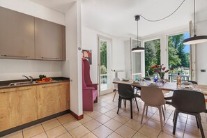 Une cuisine moderne avec des meubles en bois, un coin repas avec une table et des chaises, et une vue sur la verdure à l’extérieur.