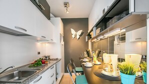 Eine moderne Küche mit weißen Schränken, einer Granitabdeckung, einer Spüle und einem Essbereich mit zwei Stühlen und einem Tisch.