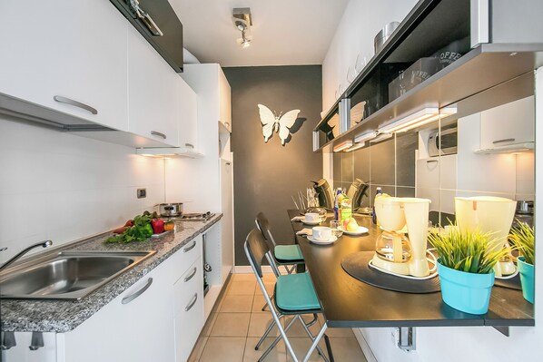 A modern kitchen with white cabinets, a granite countertop, a sink, and a dining area with two chairs and a table. - Porto Letizia T1, Porlezza, Italy (Porlezza)