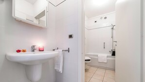Ein modernes Badezimmer mit einem weißen Waschbecken, einem Spiegel und einer Duschkabine.