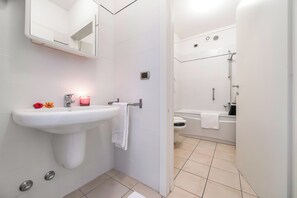 A modern bathroom with a white sink, mirror, and shower area.