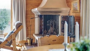 Ein gemütliches Blockhaus-Interieur mit Holzausstattung, Kamin, Fernseher und einem Fenster mit Vorhängen.