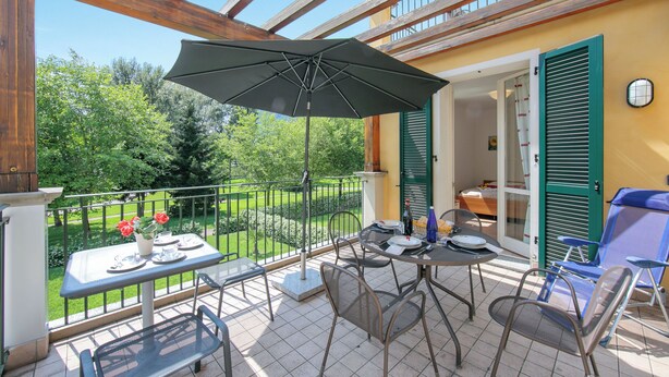 En balkon med et bord, stole og en parasol.