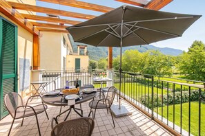 Une terrasse avec une table dressée pour le dîner, des sièges d’extérieur et une vue sur un paysage montagneux.