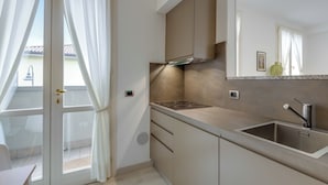 Et moderne køkken med en stålvask, indbygget komfur og et vindue med gardiner.