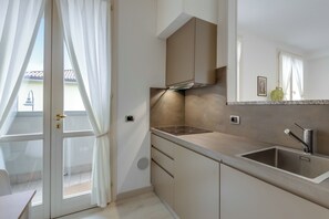 A modern kitchen with a stainless steel sink, a built-in stove, and a window with curtains.