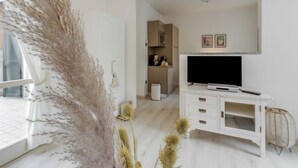 En moderne stue med et hvidt tv-møbel, et fladskærms-tv og et vindue med udsigt.