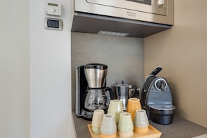 A kitchenette with a coffee maker, a kettle, and a Nespresso machine.
