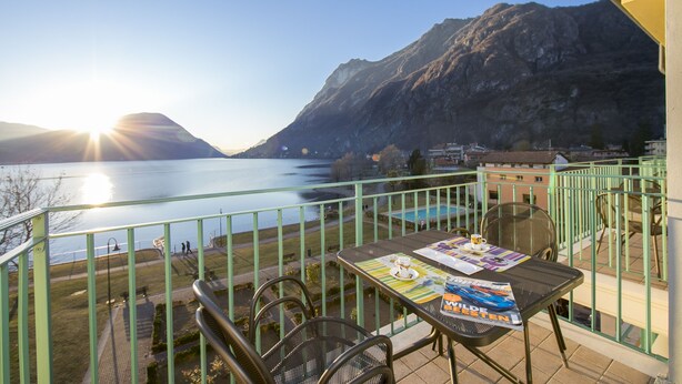 A balcony with a table, chairs, and a view of a lake and mountains. - Porto Letizia T13, Porlezza, Italy (Porlezza)