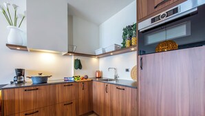 Une cuisine moderne avec des meubles en bois, un four encastré et une machine à café.