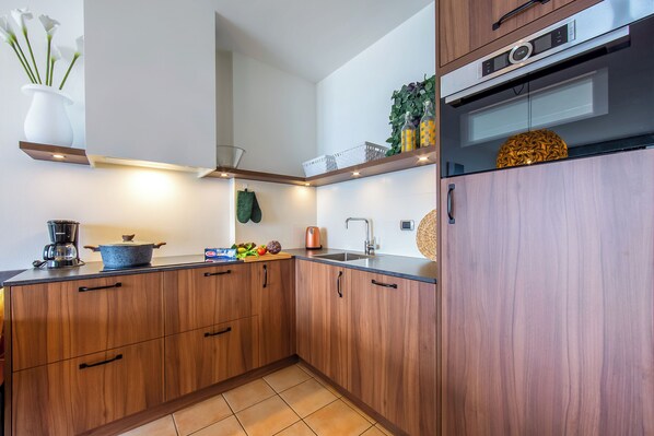 A modern kitchen with wooden cabinets, a built-in oven, and a coffee maker.