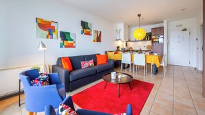 Un salon moderne avec un canapé, des fauteuils, une table à manger et des œuvres d’art accrochées aux murs.